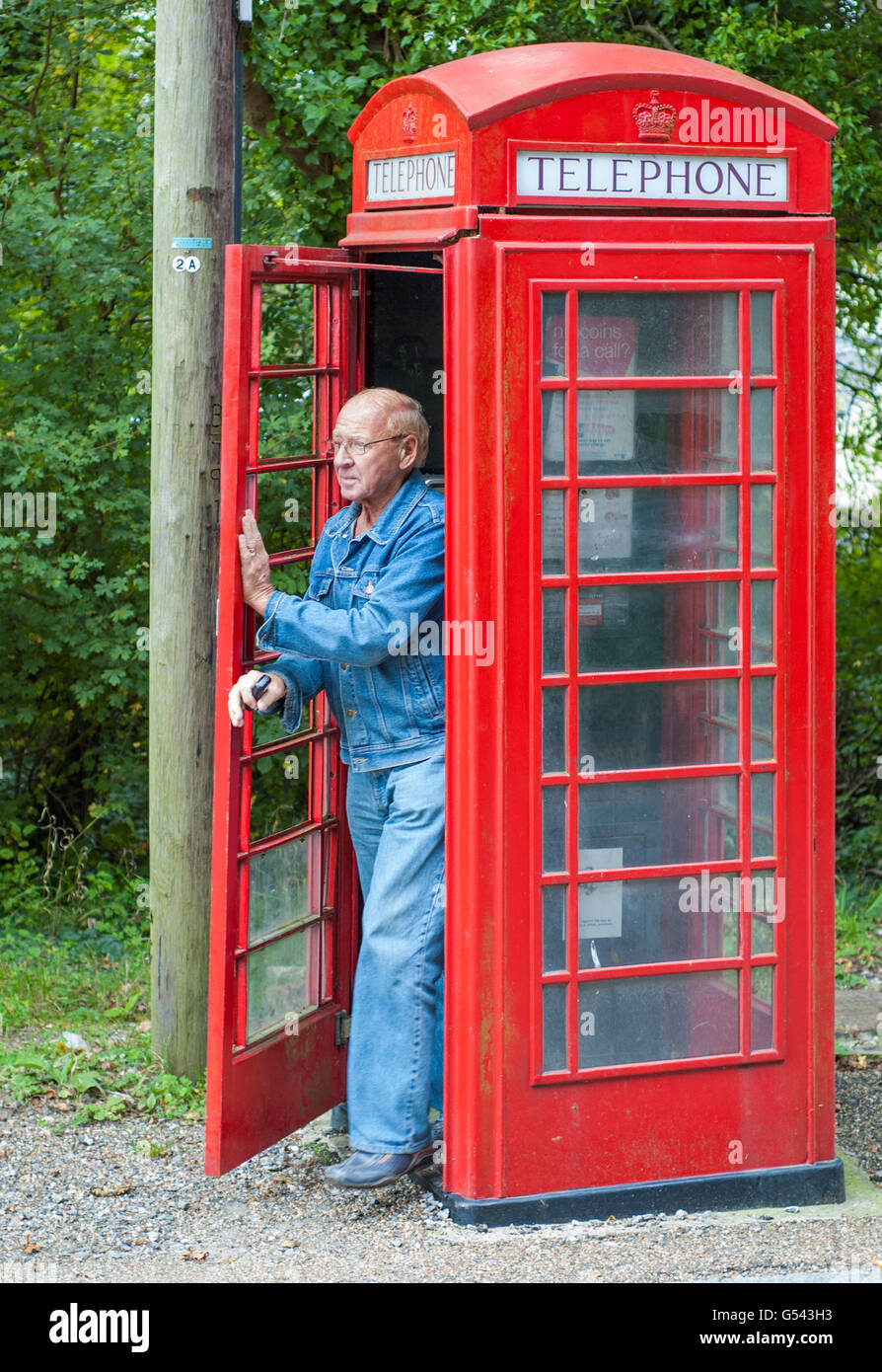 man-walking-out-of-an-old-style-british-red-telephone-box-in-amberley-G543H3.jpg