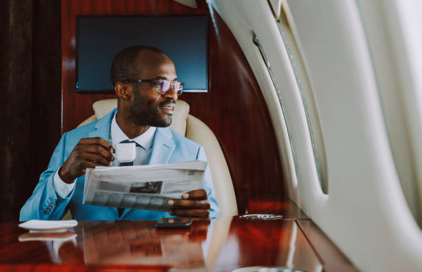 male-entrepreneur-with-coffee-cup-and-newspaper-looking-through-window-in-airplane.jpg
